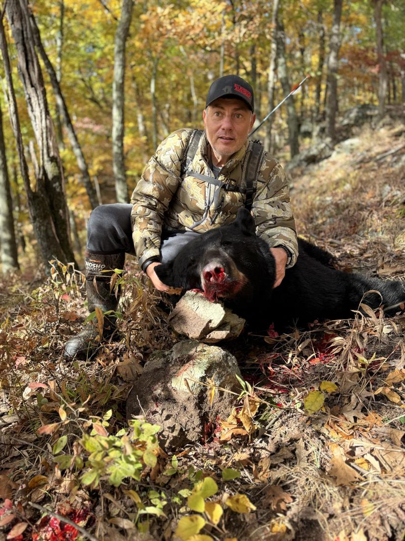 Hunter with a black bear in fall woods
