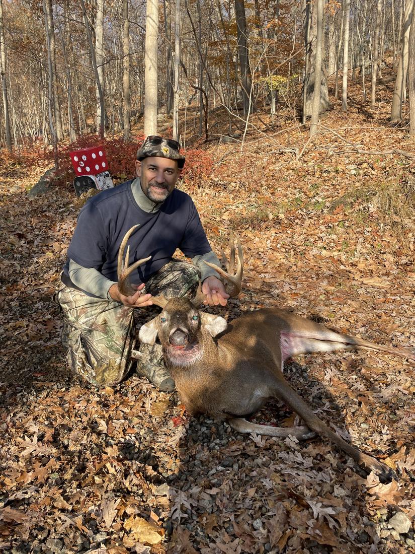 Hunter kneeling with a whitetail buck