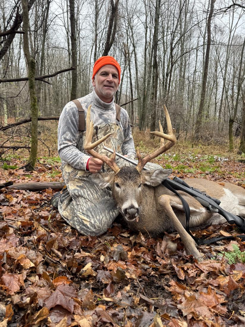 Hunter in blaze orange with a whitetail buck